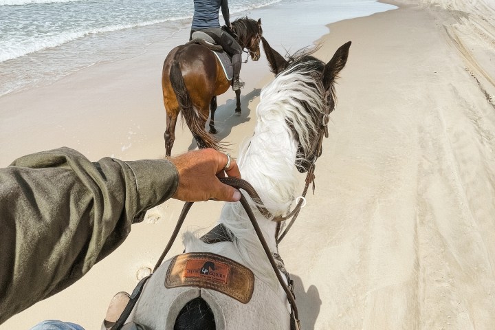 a man horse riding on the beach